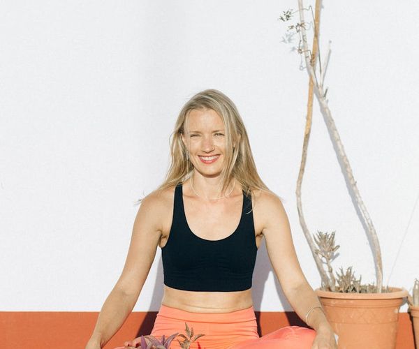 Person in a powerful warrior yoga pose, silhouetted against a bright light.